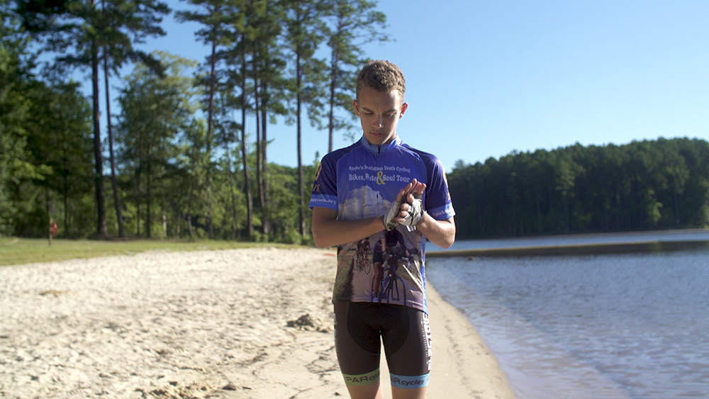 Young Spoke'n Revolution bike rider on a break standing by a lake