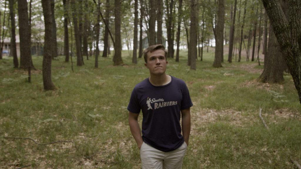 Young man in blue tshirt, walking through woods