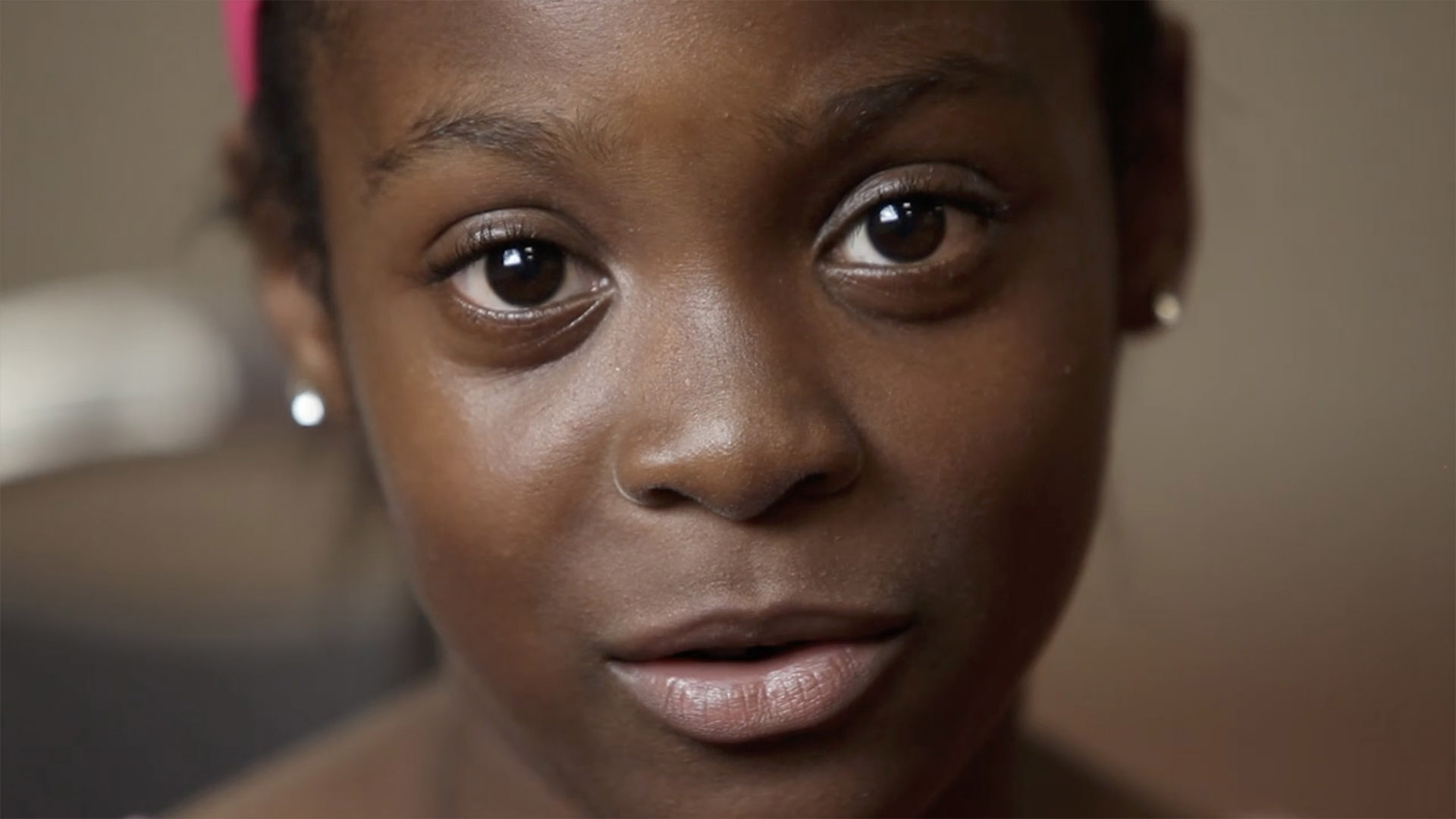 Young girl looking directly at camera reciting "It Is Possible" poem