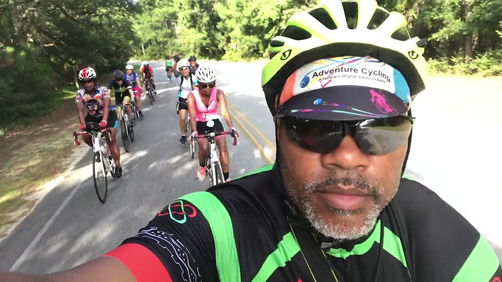 Selfie of Kevin Hicks riding a bike with group of young people riding behind him